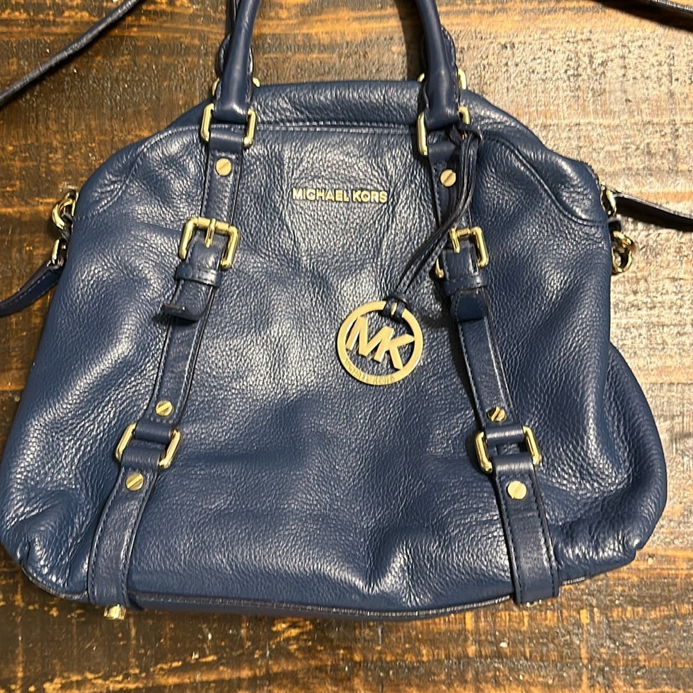 Dark blue Micheal Kors handbag with strap.